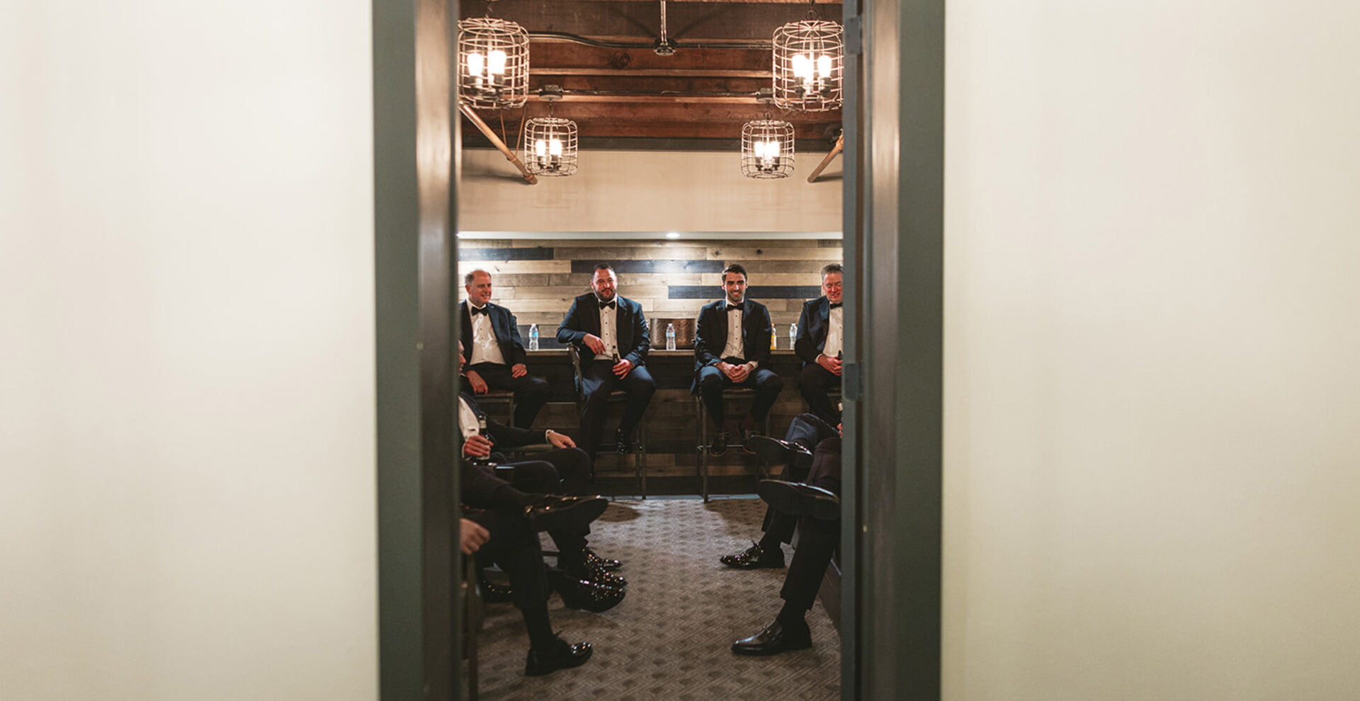 Groomsmen sitting on wooden benches in the grooms wedding suite