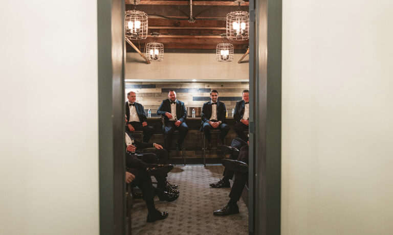 Groomsmen sitting on wooden benches in the grooms wedding suite