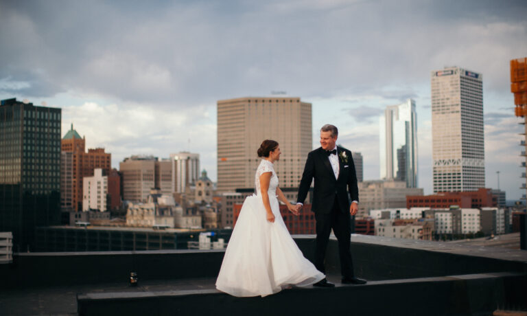 Bride and groom holding hands standing on a beam on a rooftop