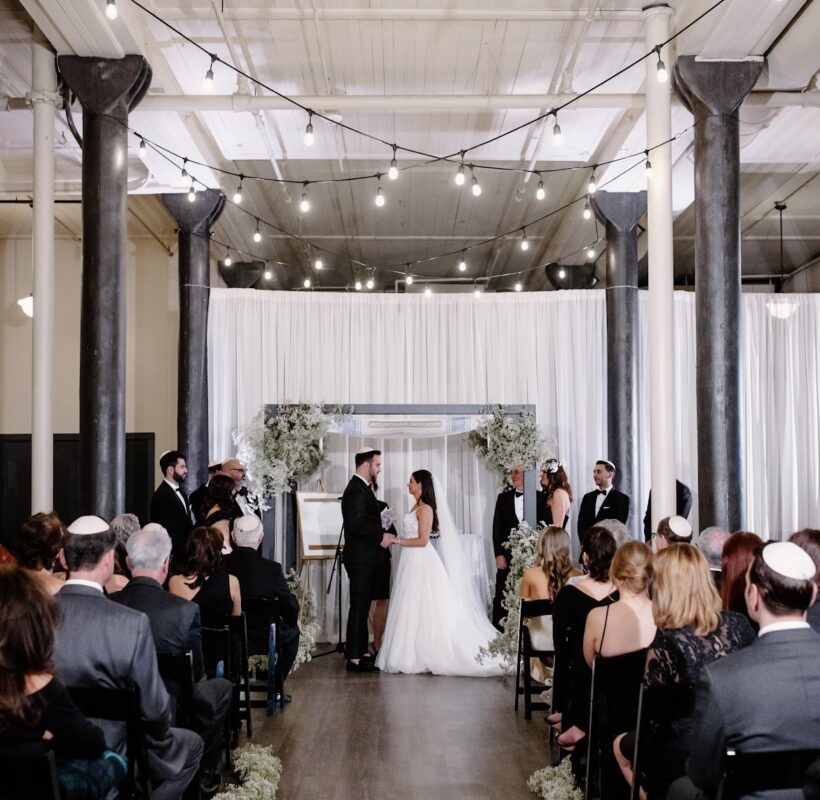 bride and groom standing at their ceremony in front of seated guests