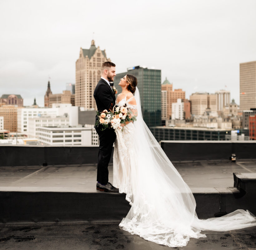 Bride and groom holding each other while standing on a metal beam on the rooftop